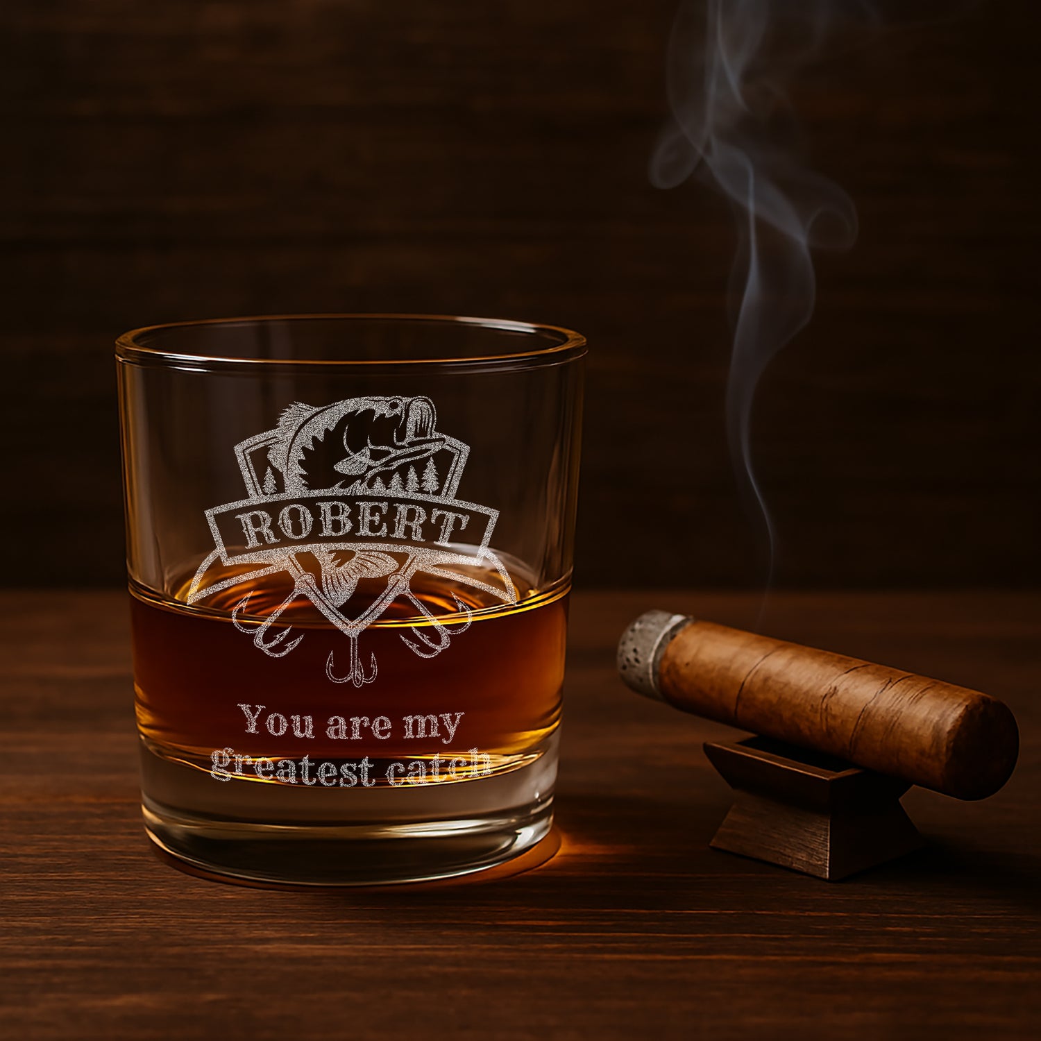 Custom rocks glass with detailed engraving of a fishing lure for fisherman gift on a bar countertop next to a cigar.